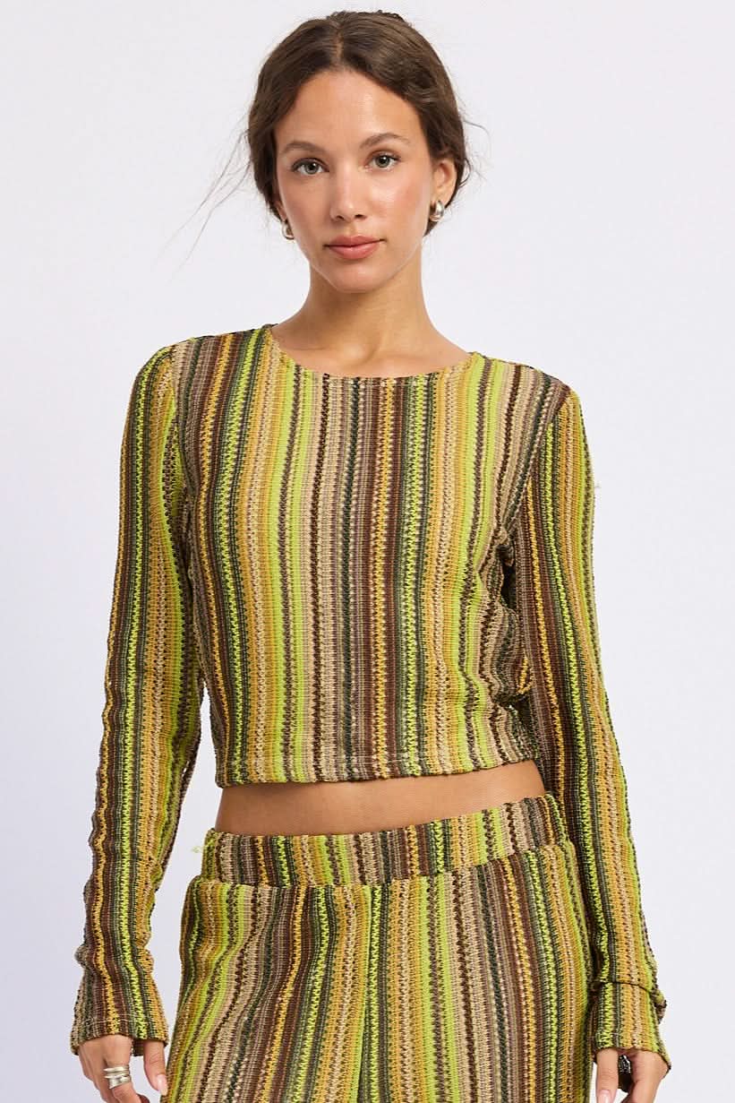 Woman wearing green and brown striped cropped crochet top with long sleeves against white background.