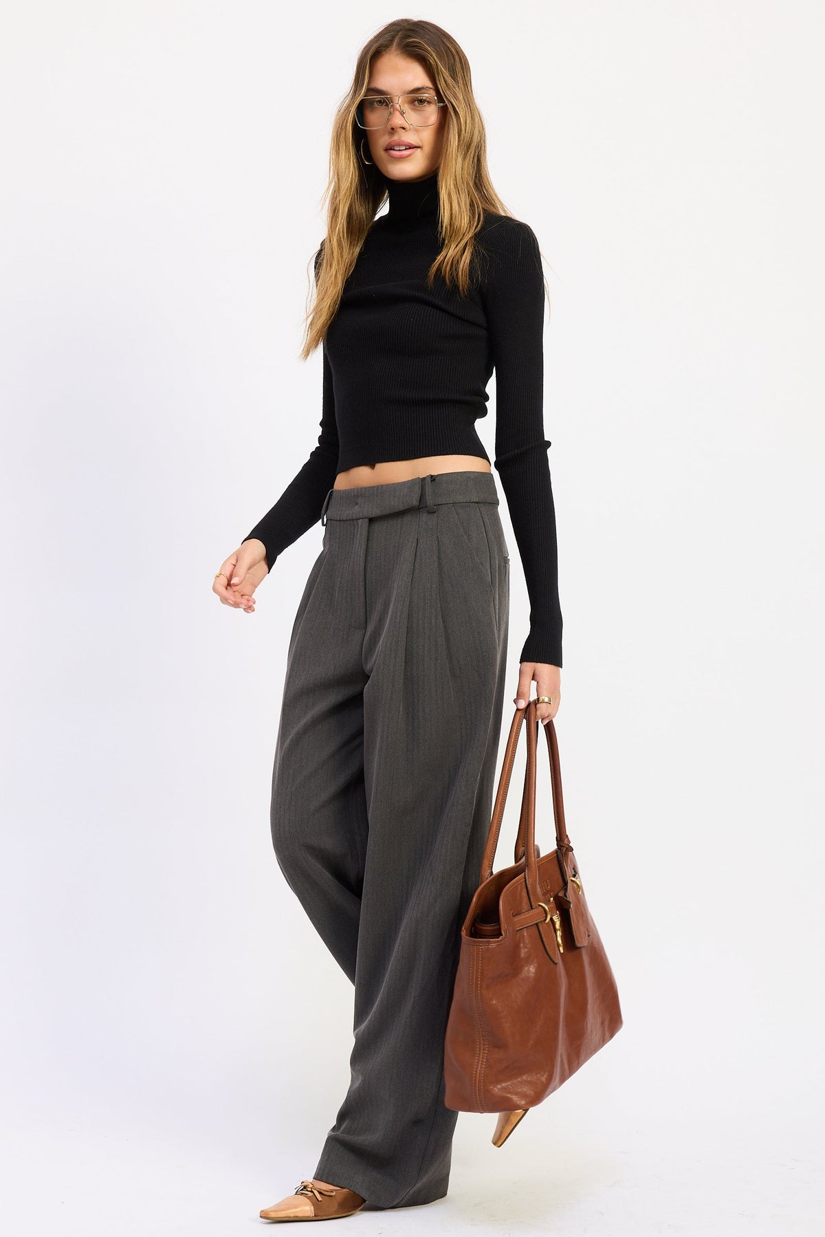 Model wearing charcoal gray Madison Wide Leg Trousers with a black fitted turtleneck and brown handbag, showing relaxed tailored fit.