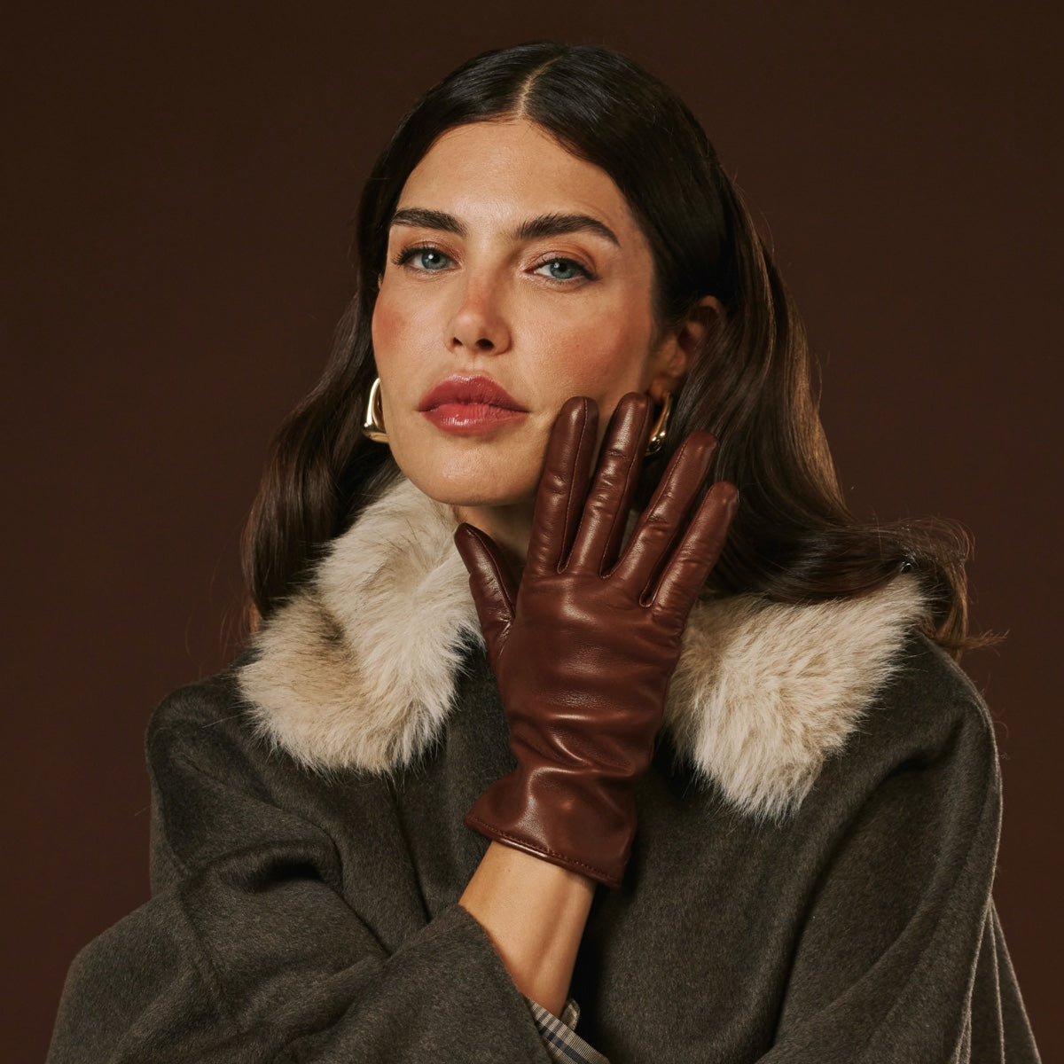 Woman wearing a brown leather glove against a dark background