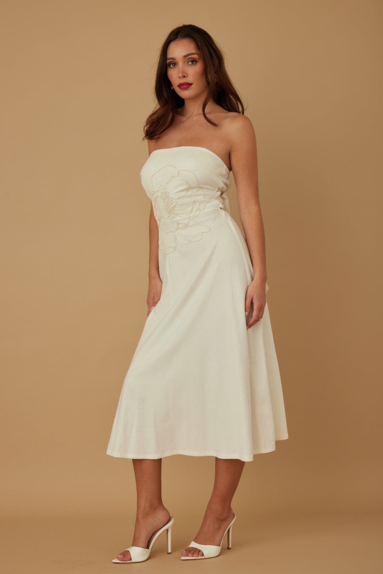 Side angle of ivory strapless midi dress showing flowy skirt and fitted bodice