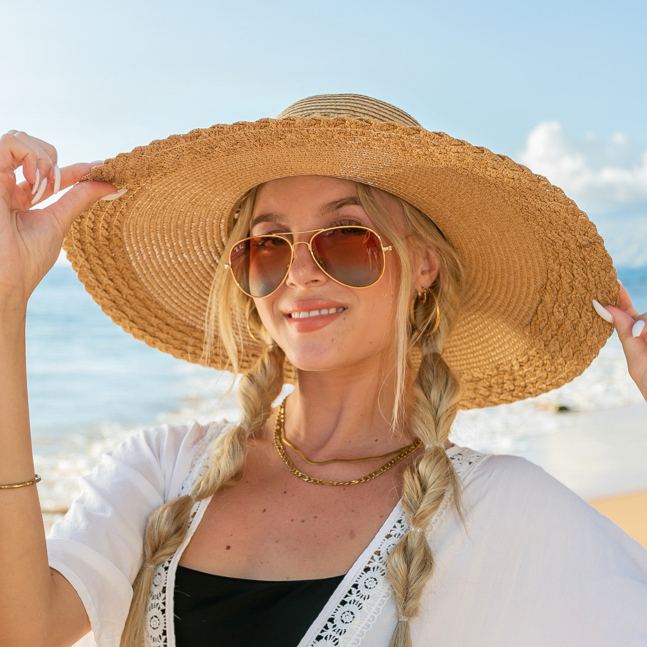 AVAH-woman wearing a large Wide Brim Straw Sun Hat that features a scallop edge design and a burlap bow accent on a beach front view