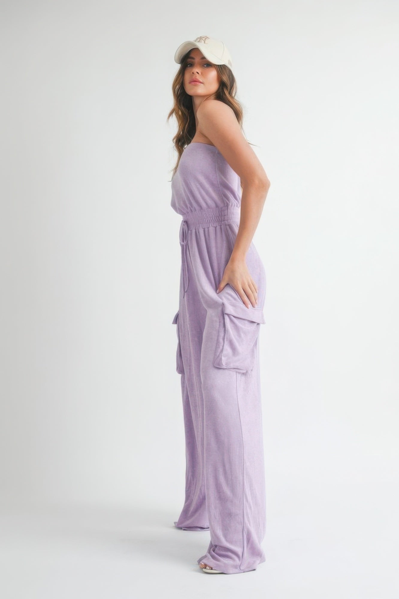 Side angle of lavender wide-leg jumpsuit with oversized cargo pockets.