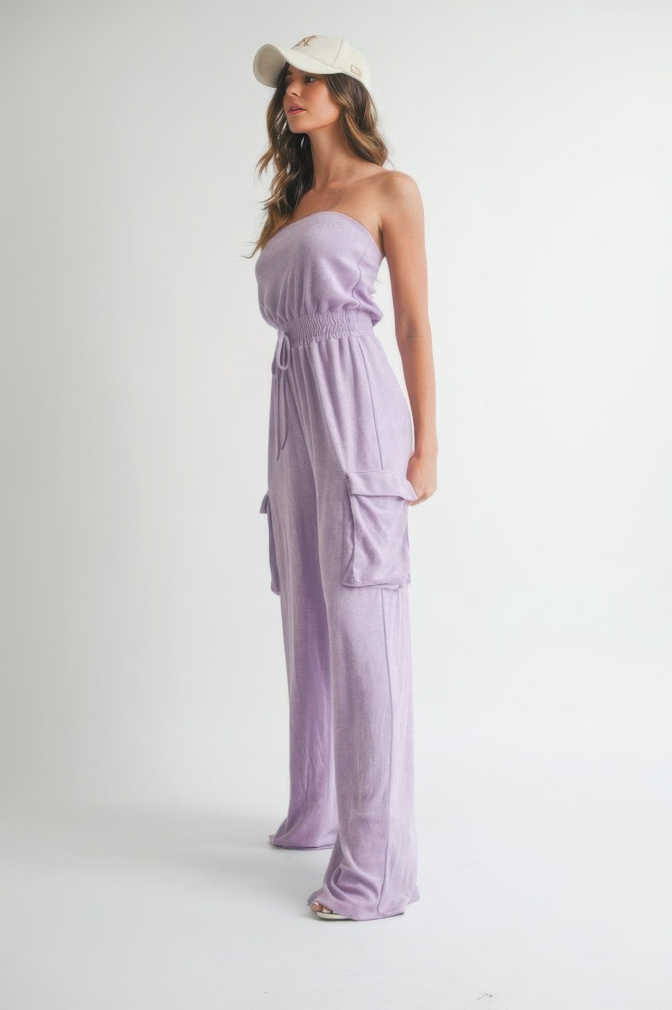 Side view of fabric texture and smocked waist of lavender jumpsuit.
