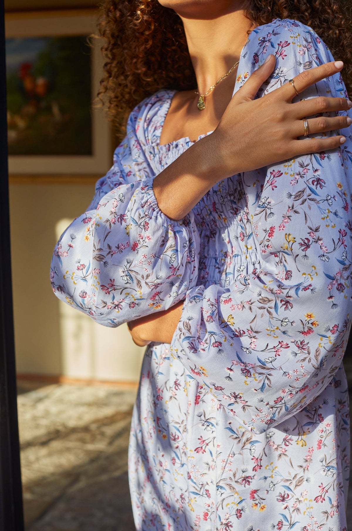 Woman wearing a lavender floral dress with a blurred indoor background