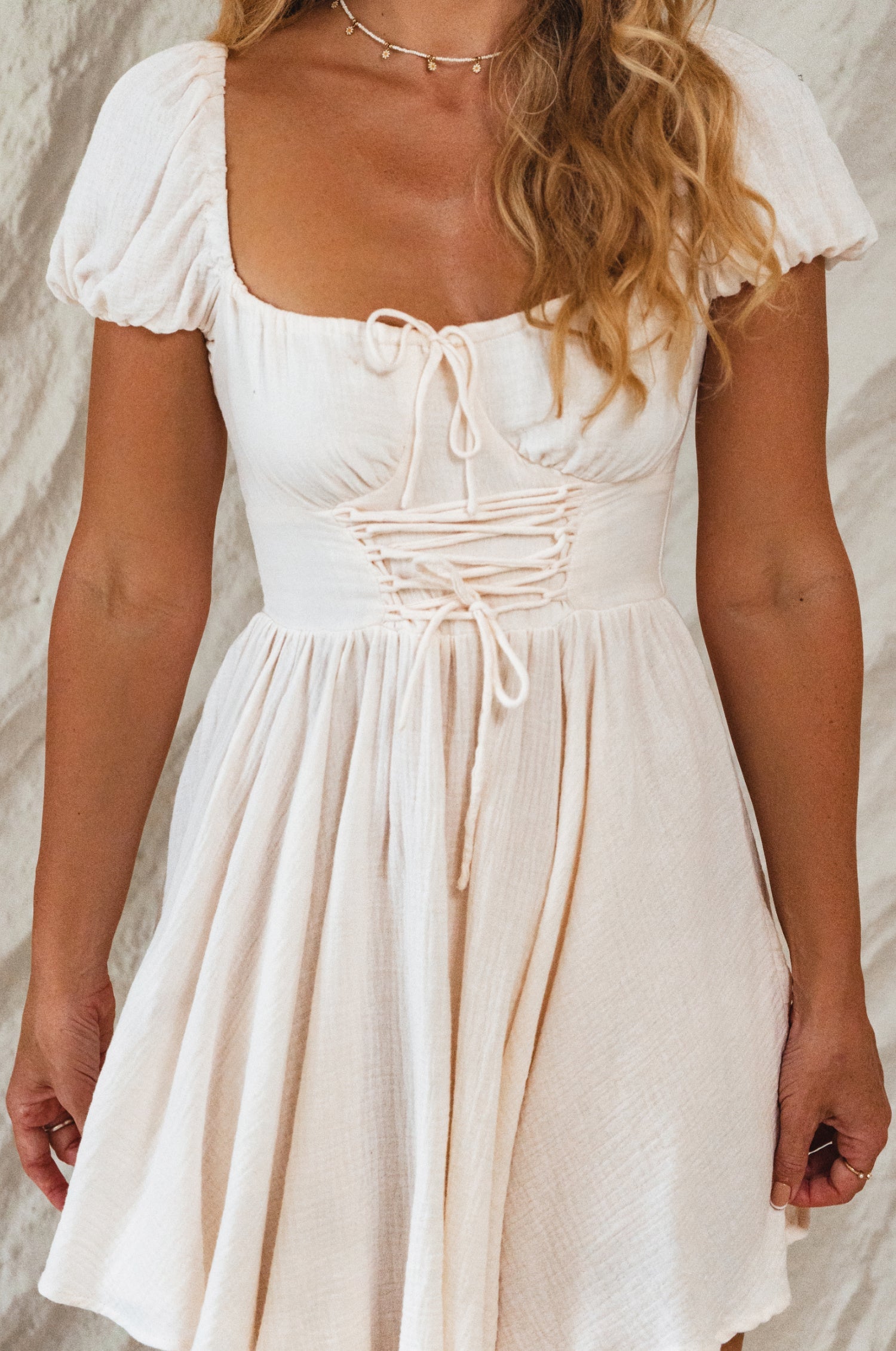Ivory dress with puff sleeves worn by a person against a neutral background, close up of bodice.