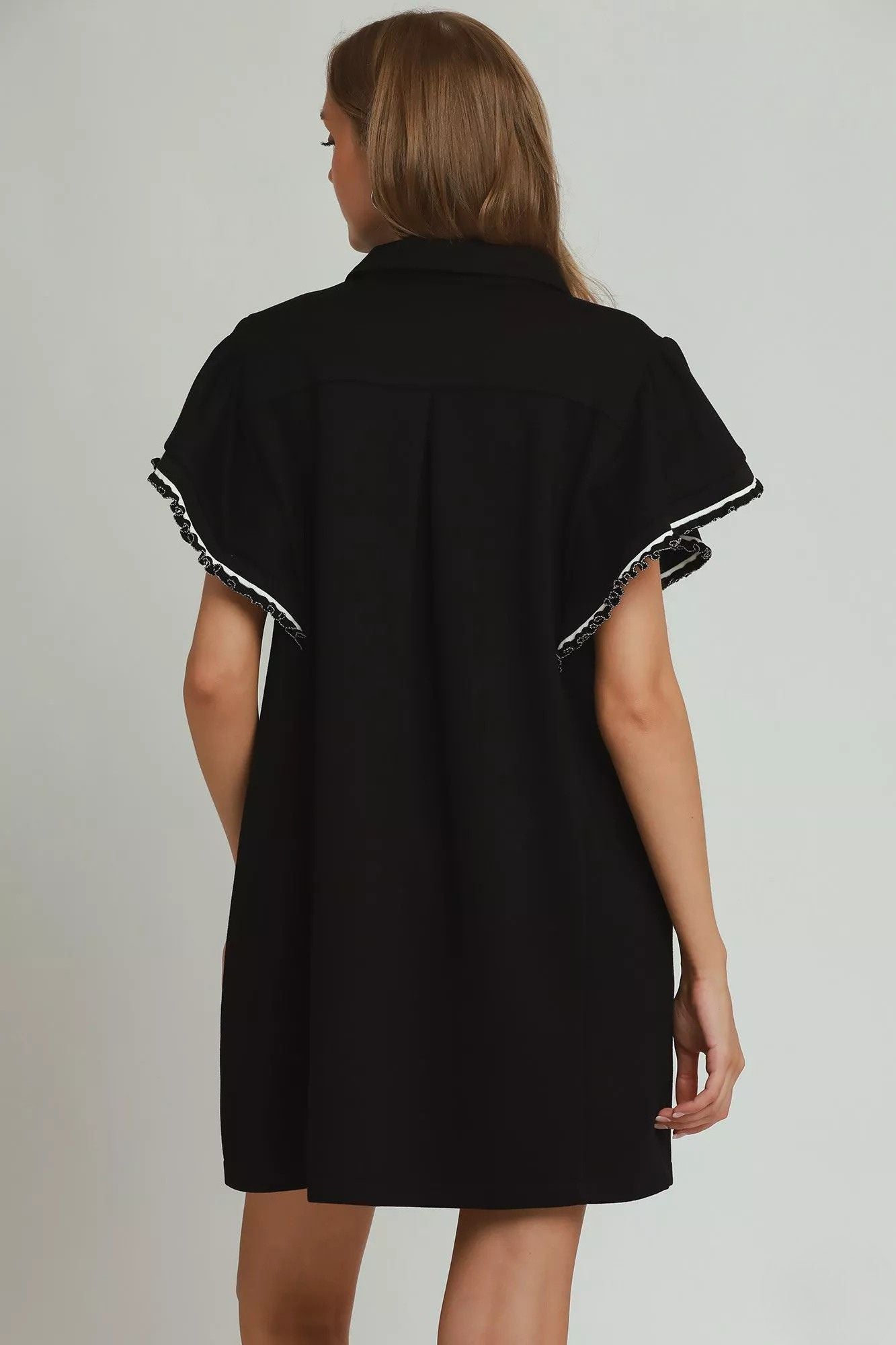 Back view of black zip collar mini dress showing clean silhouette and flutter sleeves, AVAH