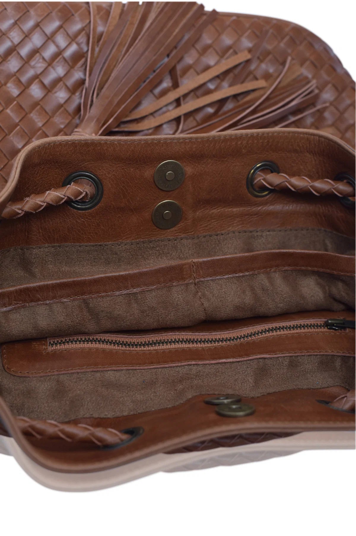 Close-up of a camel leather handbag interior showing a woven exterior texture, fringe detail, braided straps, metal snap closures, and a zippered compartment.