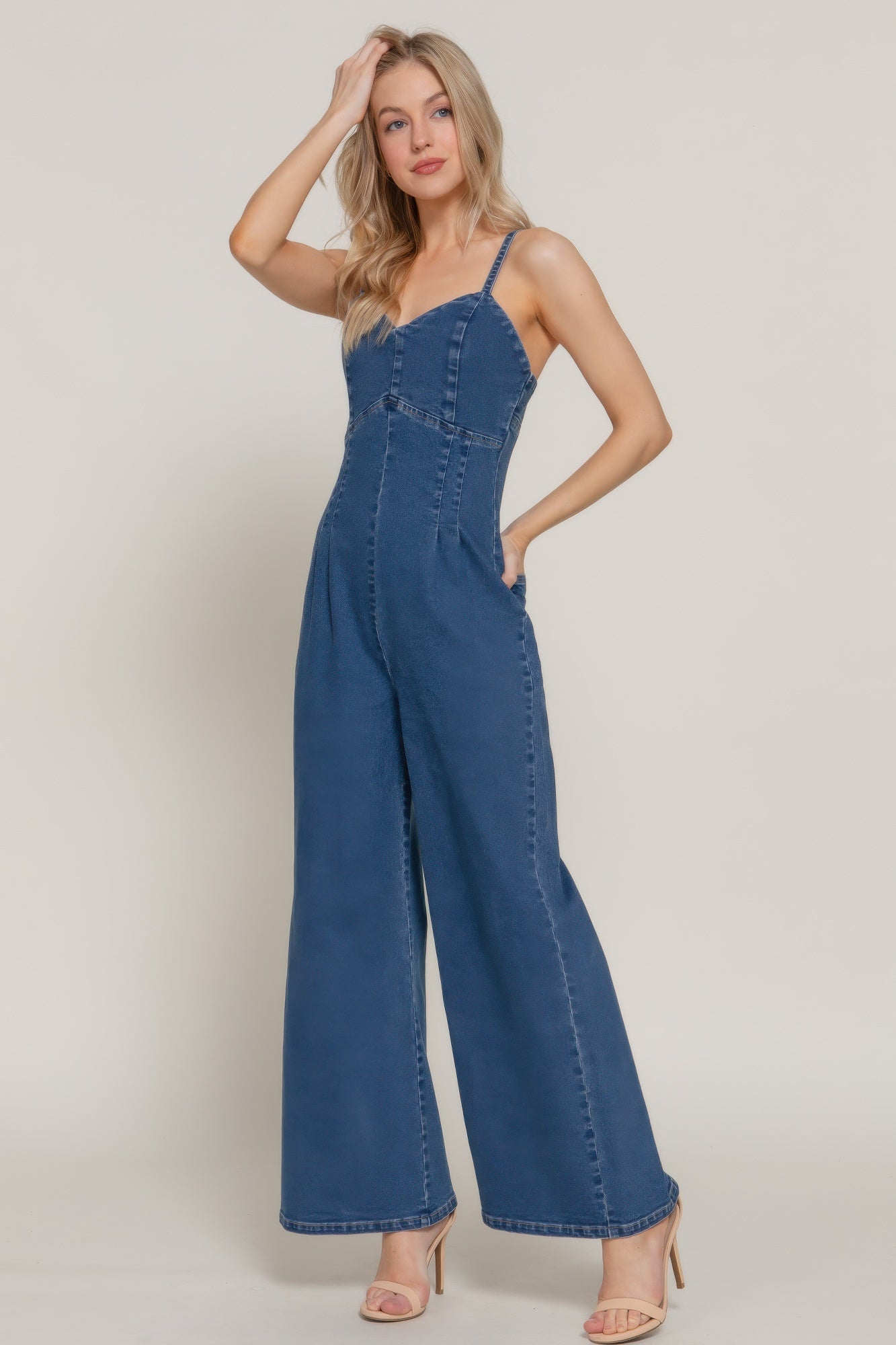 Woman posing in indigo jumpsuit with sweetheart neckline and flared legs