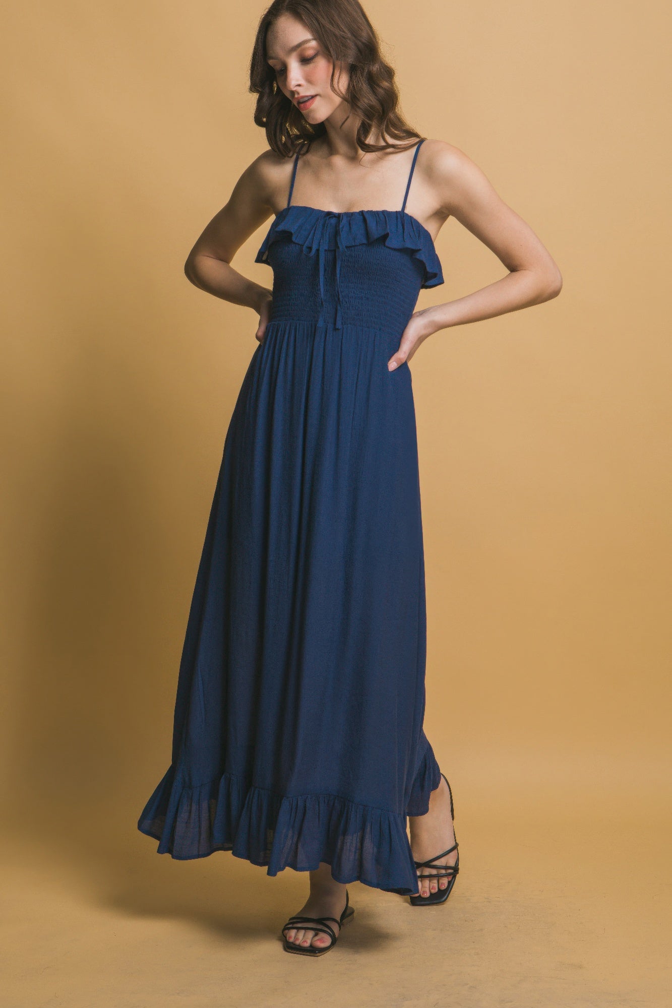 Angled view of navy ruffle maxi dress with smocked bodice and flowing skirt.