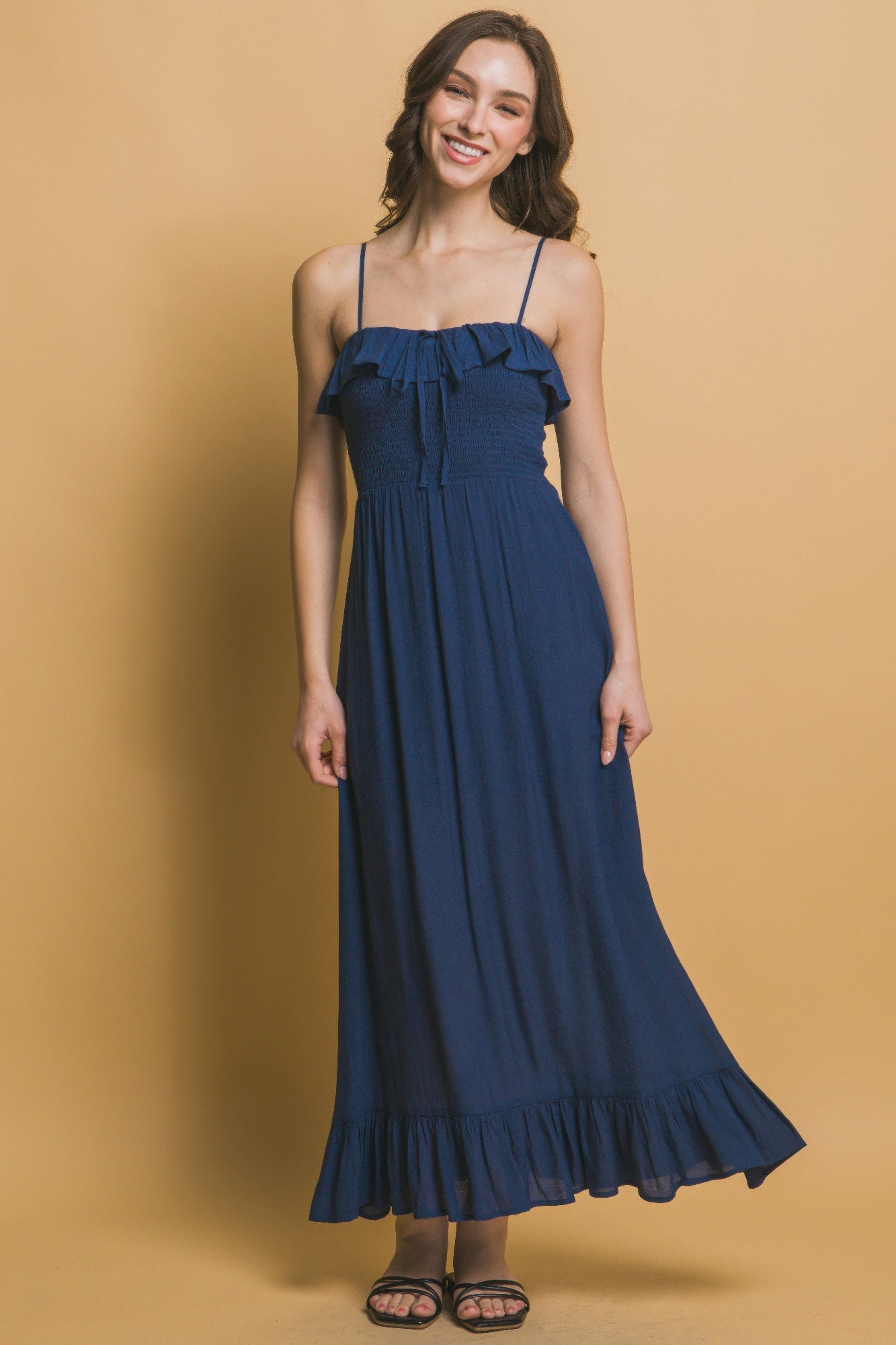 Model smiling in navy smocked maxi dress with flounce hem and gathered waist.