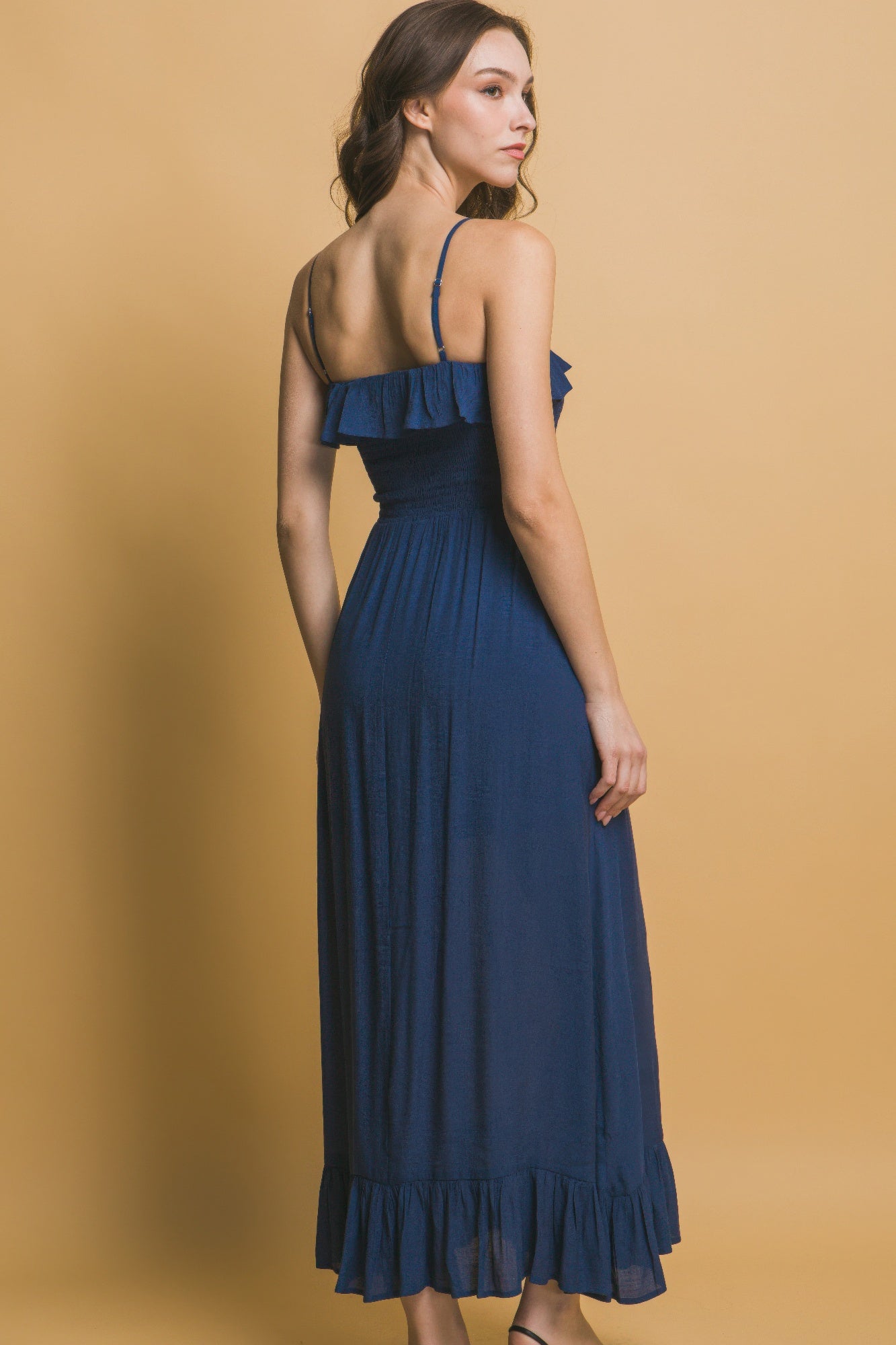 Back view of navy maxi dress with ruffled upper back and elastic waist.