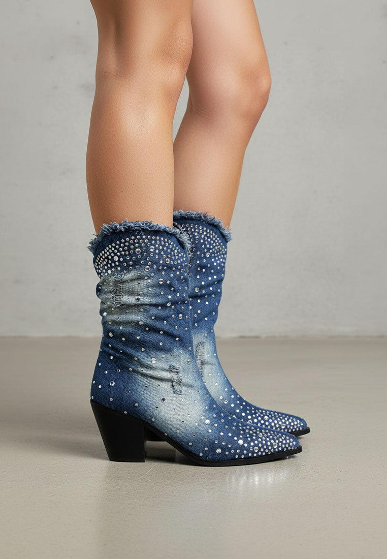Blue denim boots with rhinestone details worn by a person on a neutral background