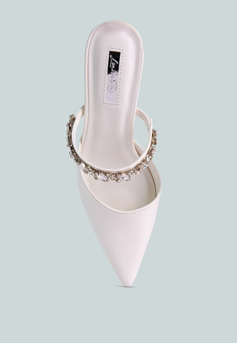 White mid-heeled shoe with a decorative diamante strap across the top on a light blue background, top view