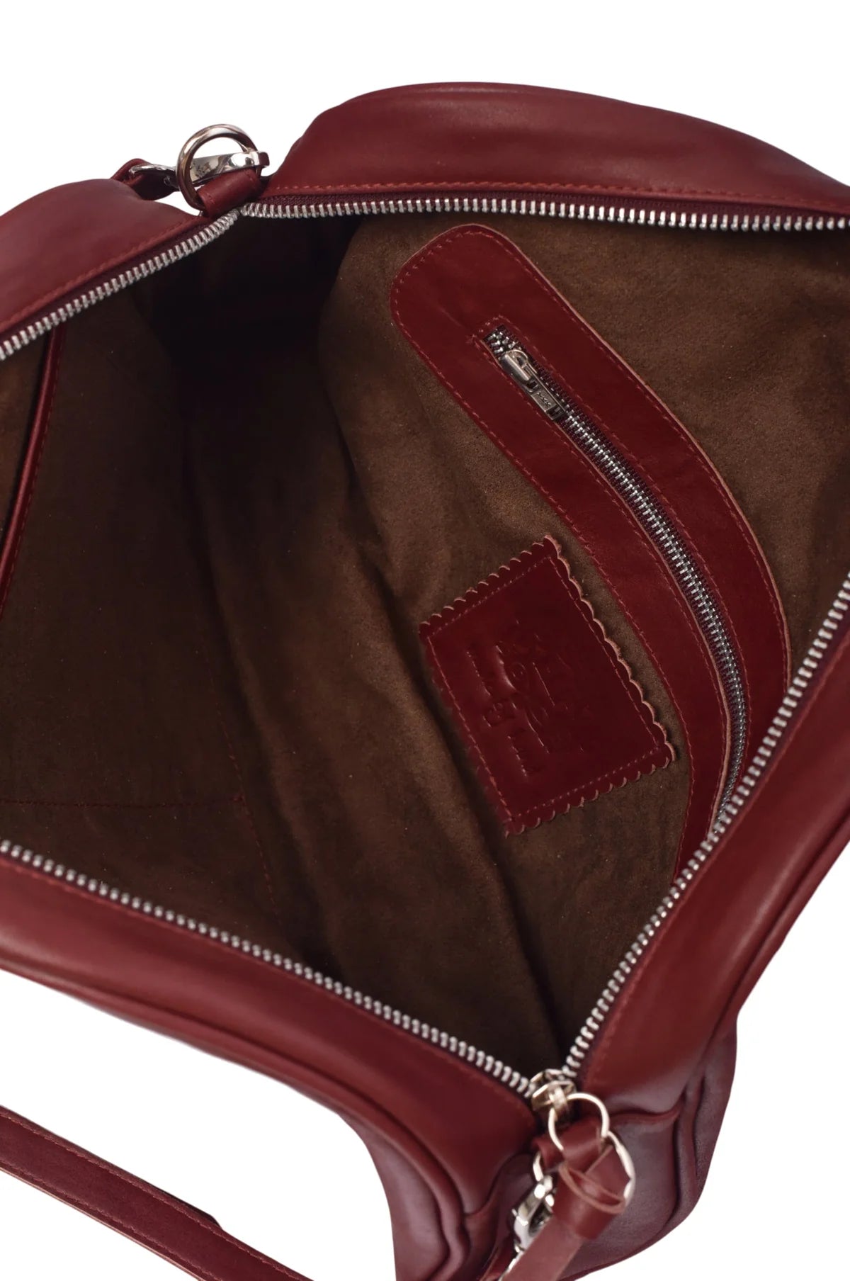 Close-up of the brown suede lining of a maroon leather bag with a visible brand logo on a white background