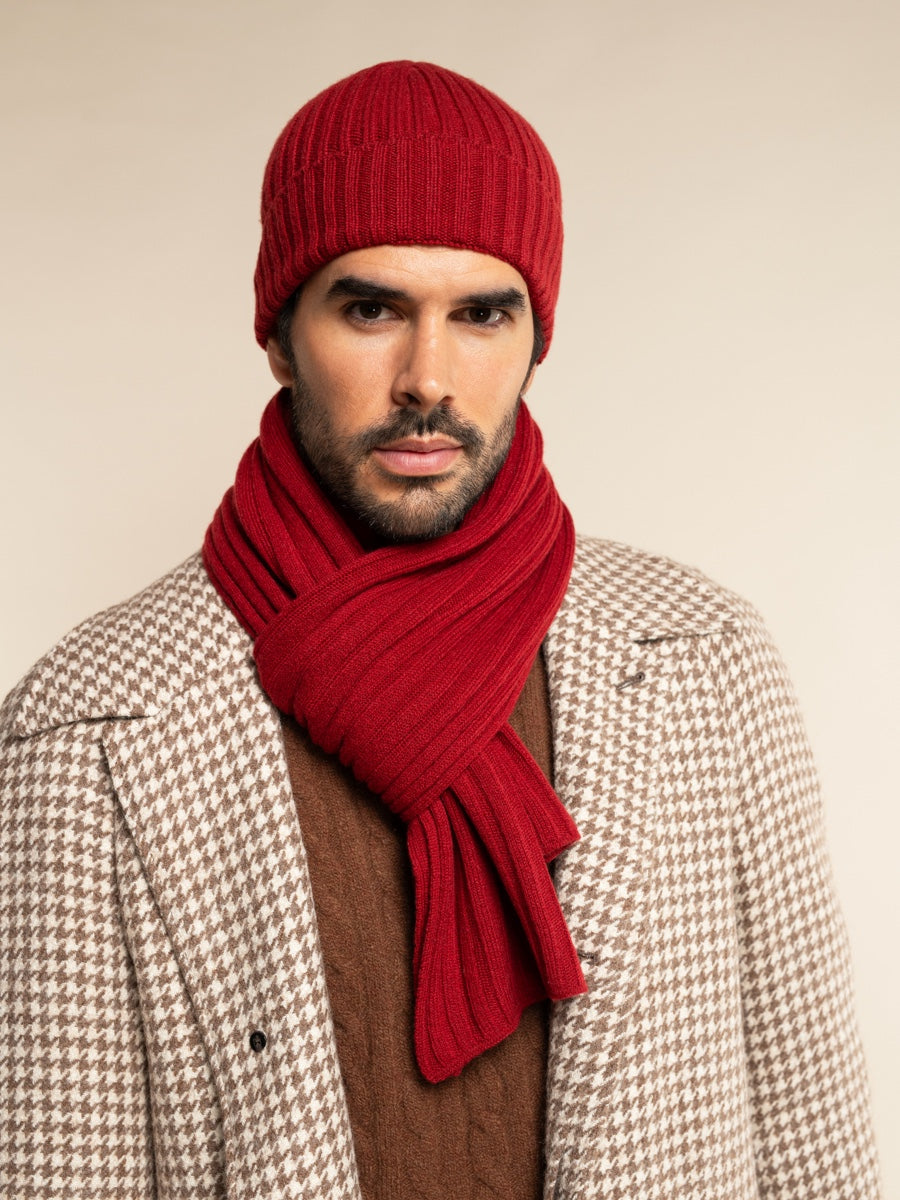 Man wearing a red cashmere knit beanie and scarf against a beige background