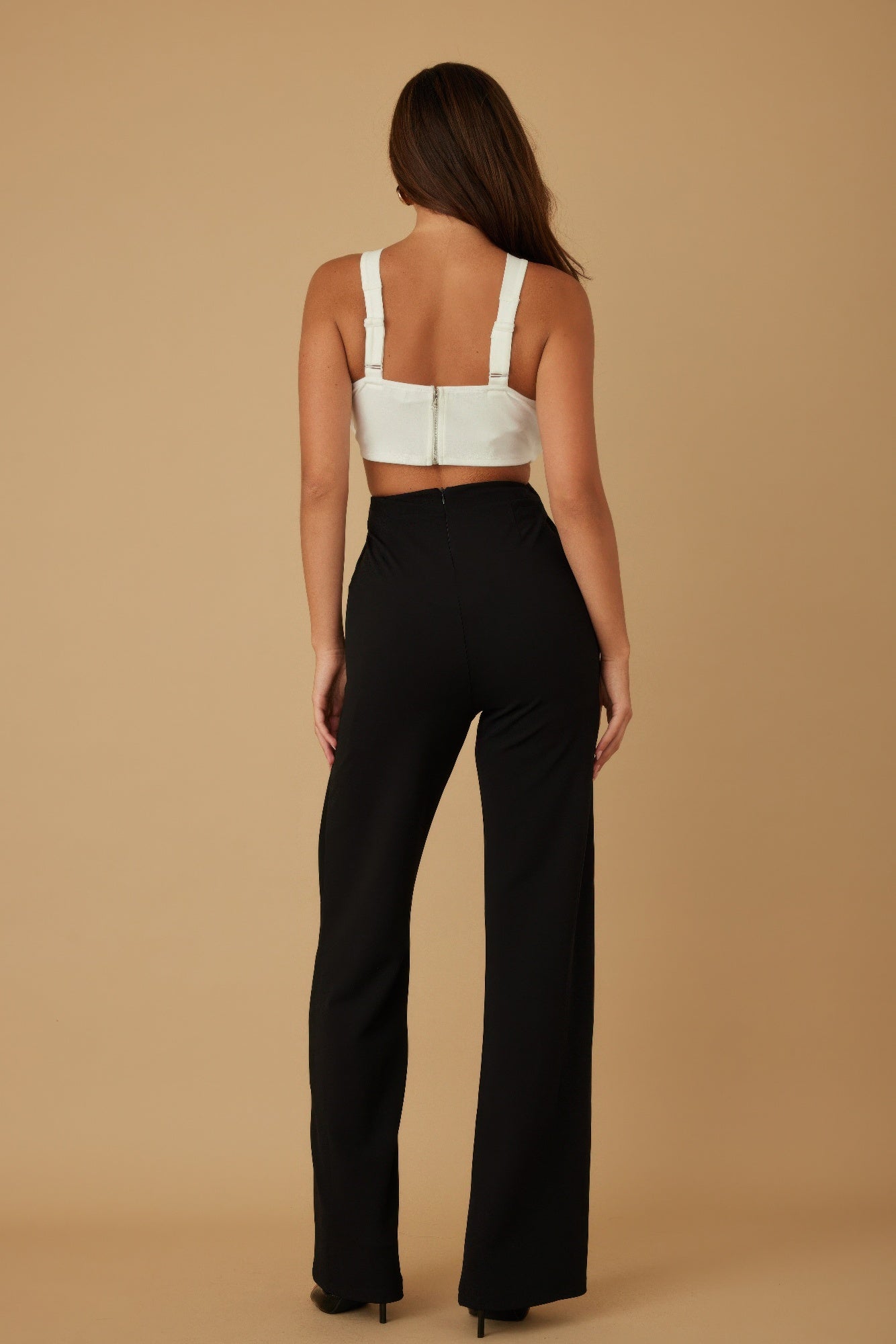 Full back view of model wearing monochrome jumpsuit with high waist and open back