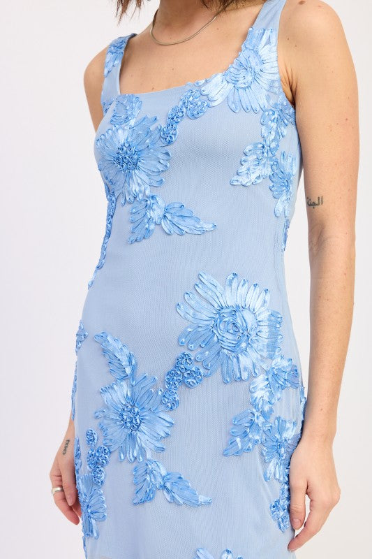 Woman wearing a light blue floral embroidered mesh mini dress with appliqué detail and open back on a white background closeup