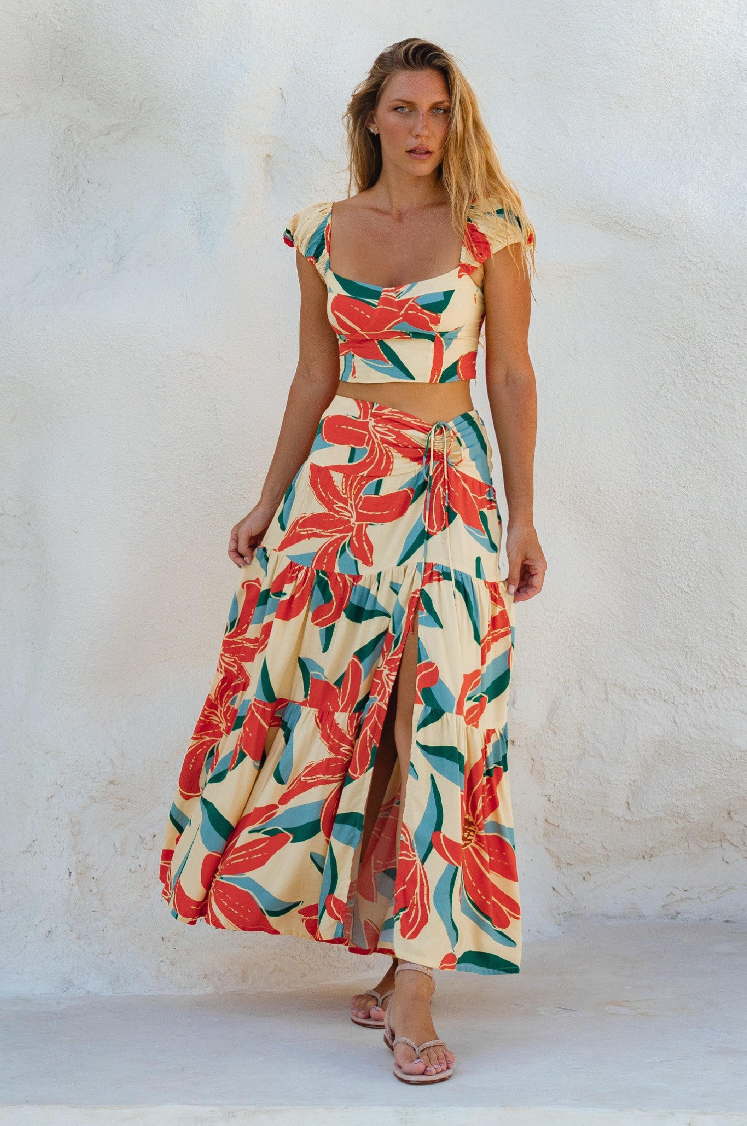 Woman wearing a colorful floral two-piece outfit against a white background