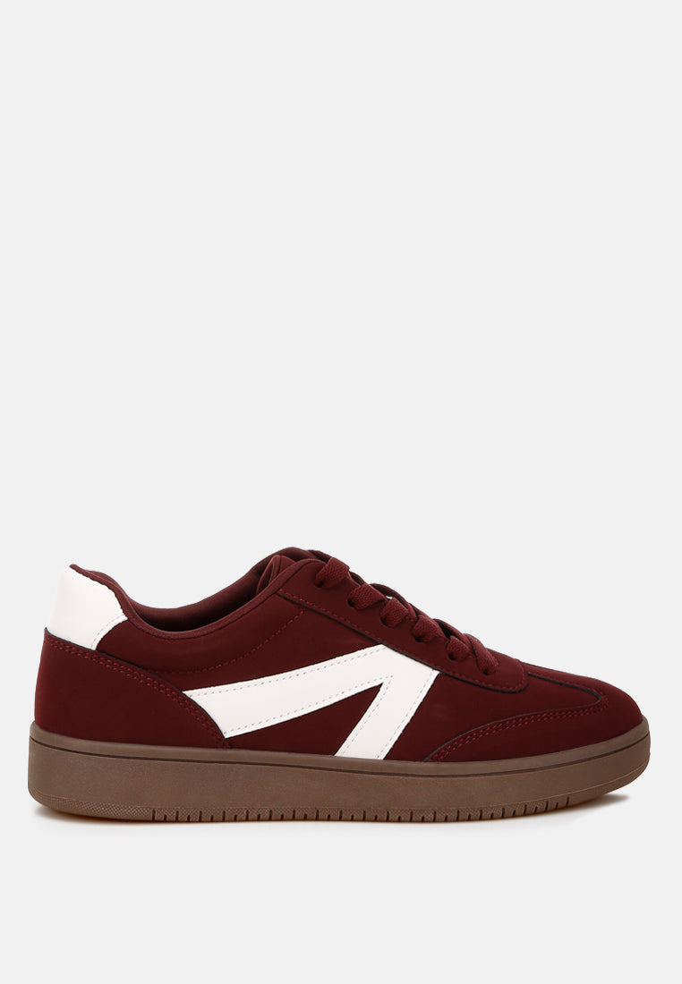 Burgundy sneaker with a white patchwork design on a light gray background