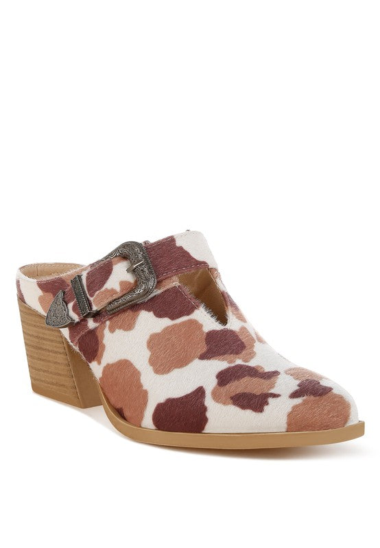 Front angled view of cow print pointed-toe mule with stacked heel and western buckle