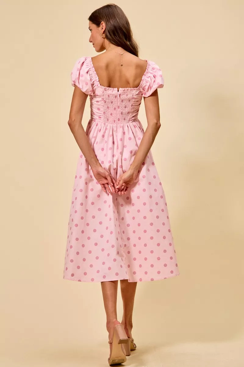 Back view of pink polka dot midi dress featuring a smocked back panel and flowing midi skirt | AVAH Collections