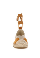 Front view of tan espadrille showing rounded woven toe and ankle ribbon detail