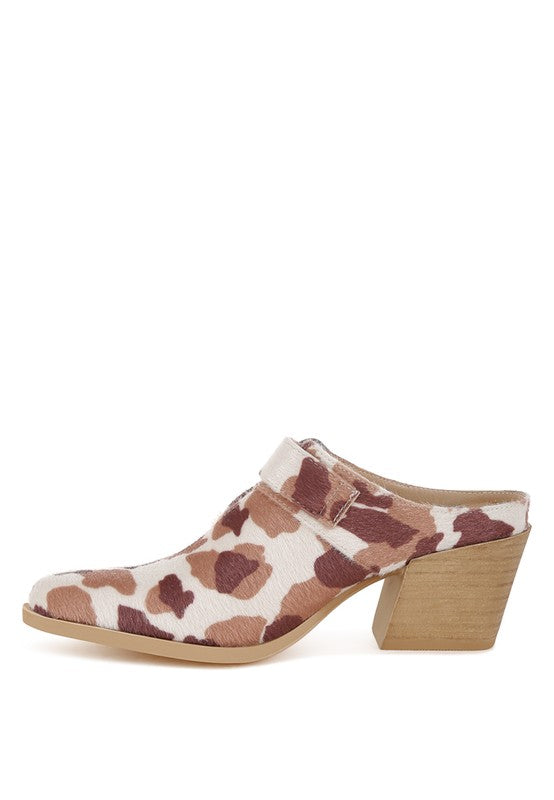 Outer profile of cow print mule with textured buckle and wooden heel
