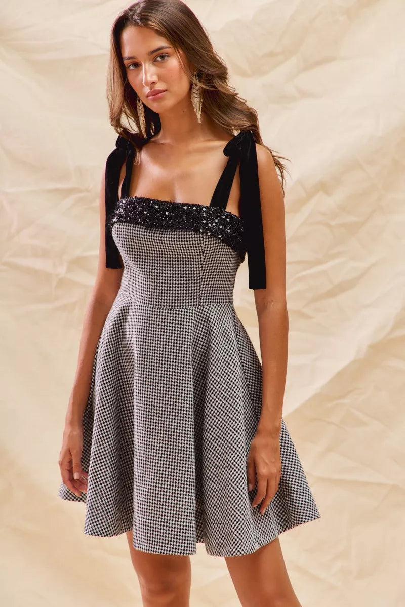 Black and white houndstooth fit and flare dress with sequin neckline trim and tie shoulder straps