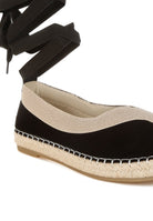 Close-up of black espadrille upper with woven beige trim and stitched sole