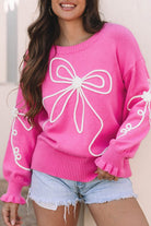 close-up of pink sweater with oversized white bow design on front