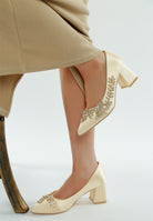 Side view of beige satin embellished block heel on model

