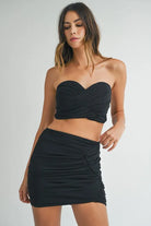 Front view of black ruched strapless crop top and mini skirt set
