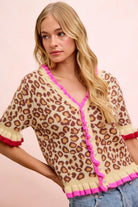Leopard print short sleeve cardigan with bright pink ruffle trim, pearl buttons and contrast ruffled cuffs, front view.