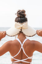wide brim straw visor hat with leopard trim worn at the beach