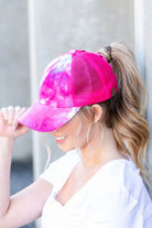 Hot pink tie dye criss cross ponytail cap worn angled front view
