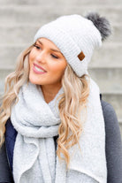 White bouclé knit hat with faux fur pom worn with scarf, angled view