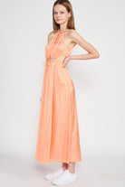 Side view of model in halter satin dress showing waist cutouts and relaxed silhouette