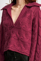 Close-up of burgundy cable-knit sweater showing deep V-neckline and textured knit.