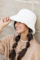 Side view of white faux-fur bucket hat styled with beige sweater

