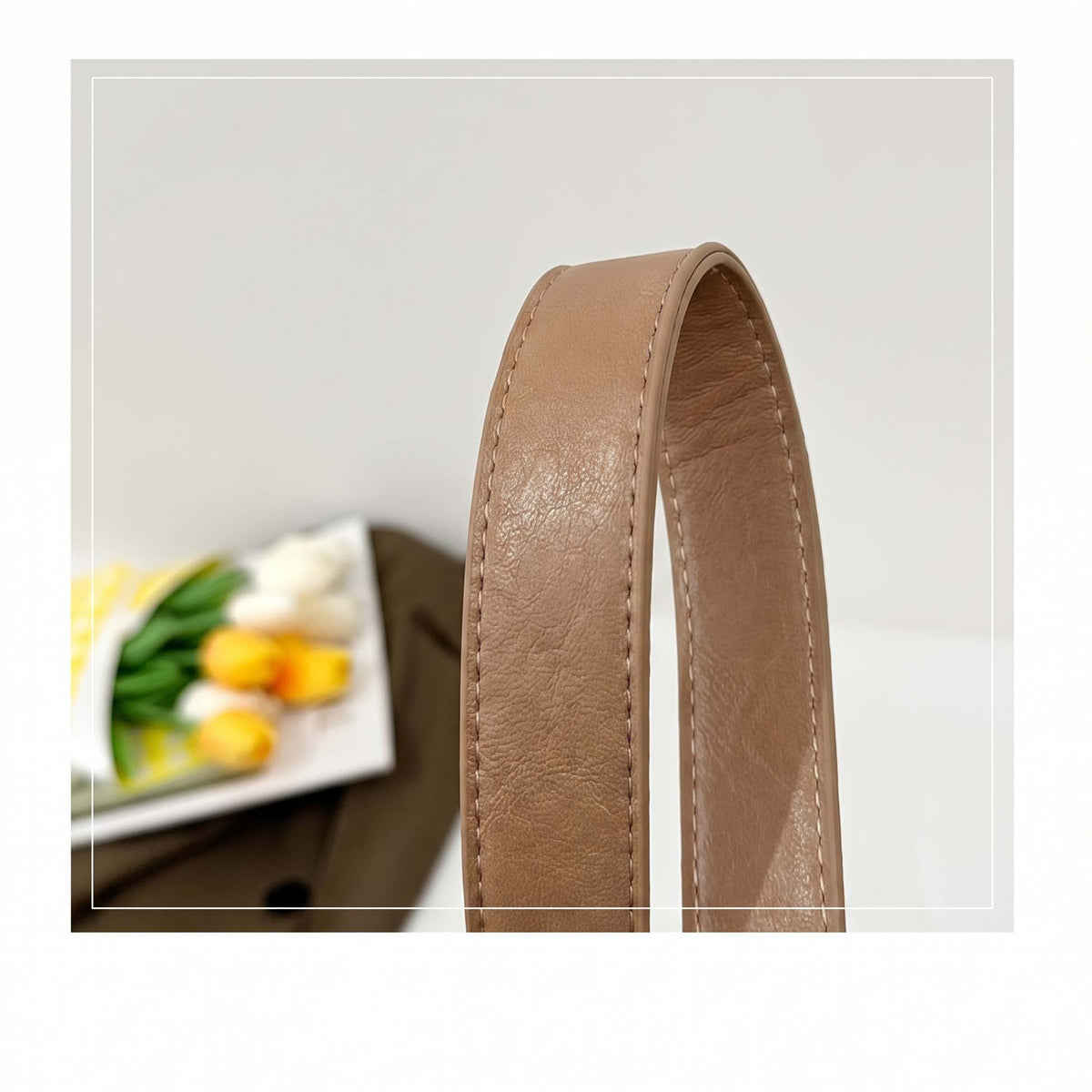 Close-up of stitched vegan leather strap on fawn suede-look hobo bag.