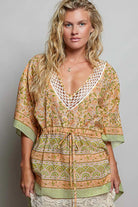Woman wearing the Sunset Bazaar Boho Top featuring a crochet V neckline, floral print, artisan inspired border details, adjustable drawstring waist, kimono sleeves, and tassel accents.