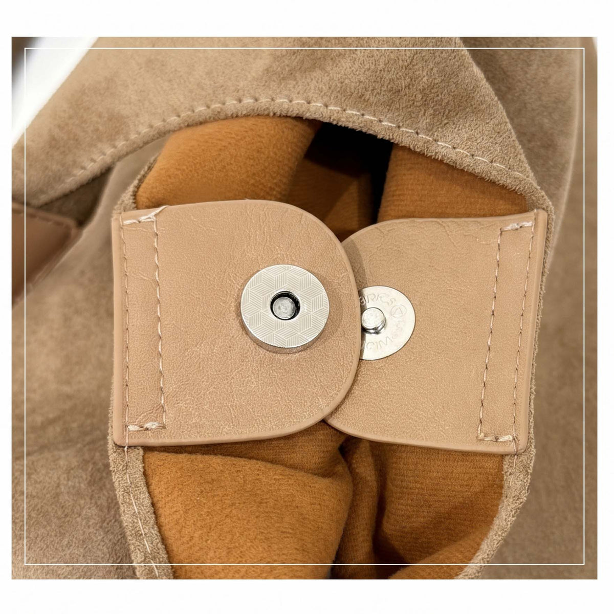 Close-up of magnetic snap closure inside fawn suede-look hobo bag.