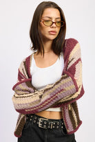 Model wearing burgundy striped cardigan draped open over white tank – folded arms pose
