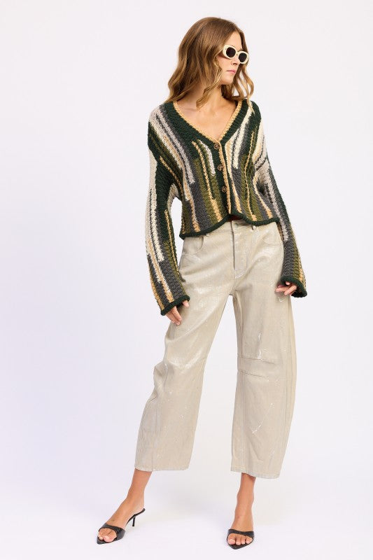 Full outfit view of olive striped cardigan styled with light pants and black heels – side angle
