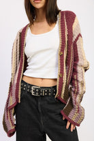 Close-up of burgundy multi-stripe cardigan with textured knit and button detail
