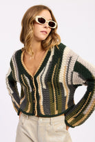 Model in olive striped cardigan looking to the side – cropped fit and sleeve detail visible
