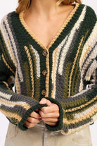 Close-up of olive and cream striped cardigan with wooden buttons and crochet-style knit
