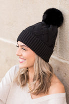 Black knit winter hat with faux fur pom, front view
