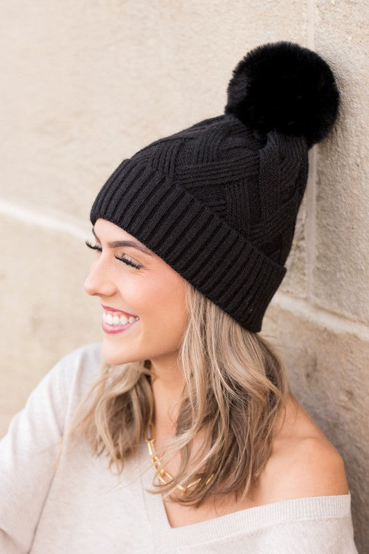 Black knit winter hat with faux fur pom, front view
