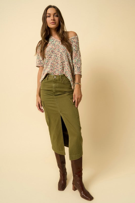 Front view of model wearing olive cargo denim midi skirt with floral top and brown boots.
